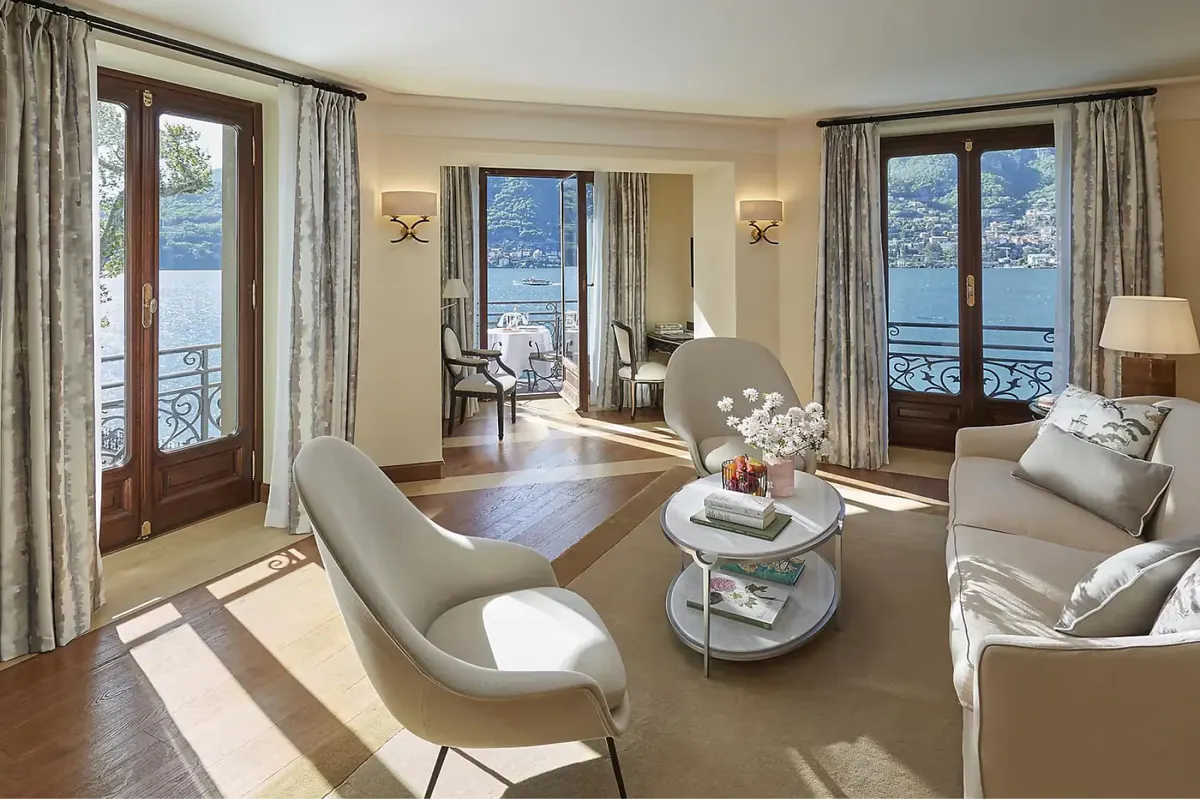 Contemporary suite with cream furnishings, glass doors opening to lake views and mountains