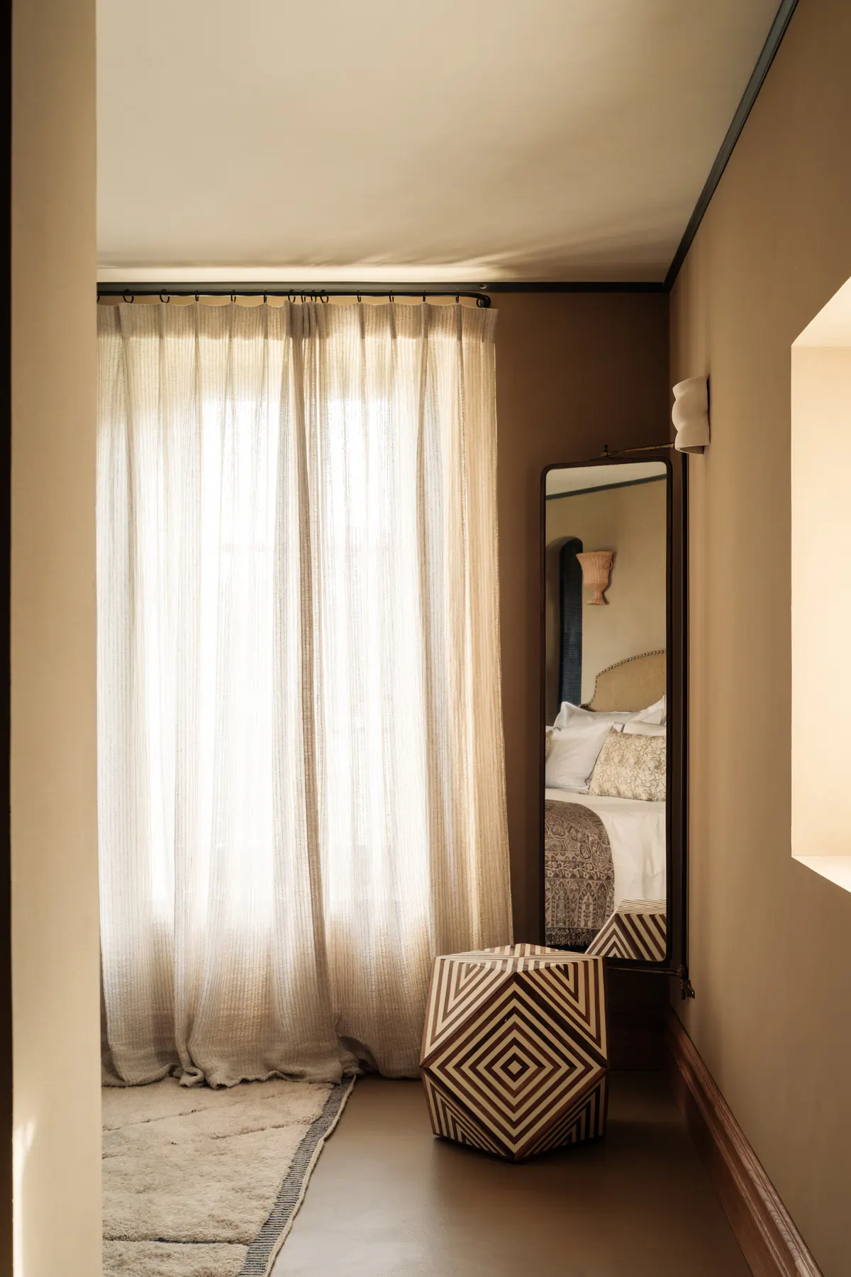 Narrow dressing hallway with sheer linen curtains, tall mirror, geometric-woven seating bench