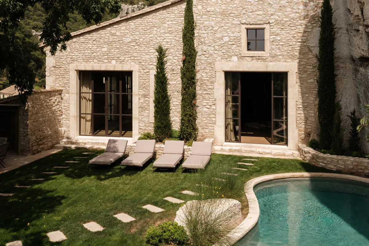 Stone facade, gravel terrace with sun loungers, aquamarine pool, white cliff backdrop