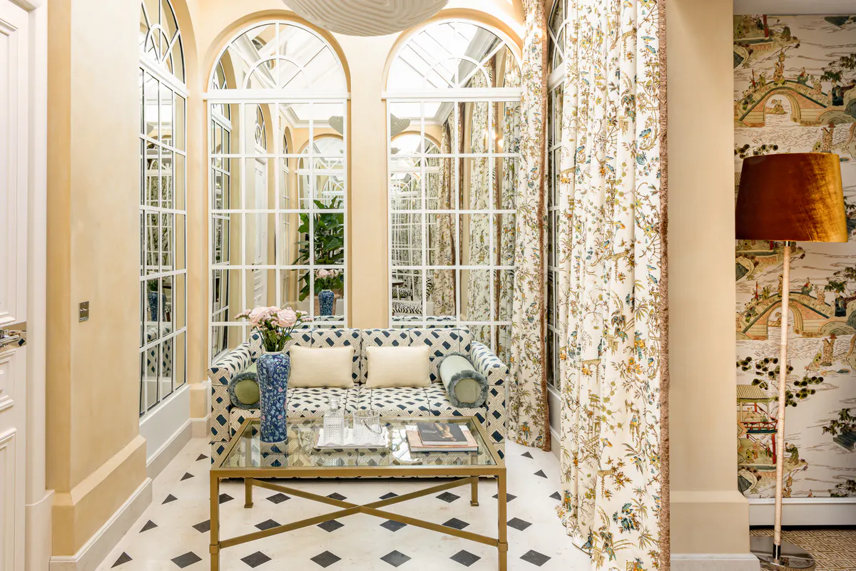 Glass-enclosed patio room with geometric pattern furnishings, arched transom windows