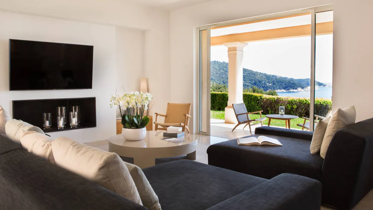 Bedroom with dark blue cushions and mountain views through glass doors
