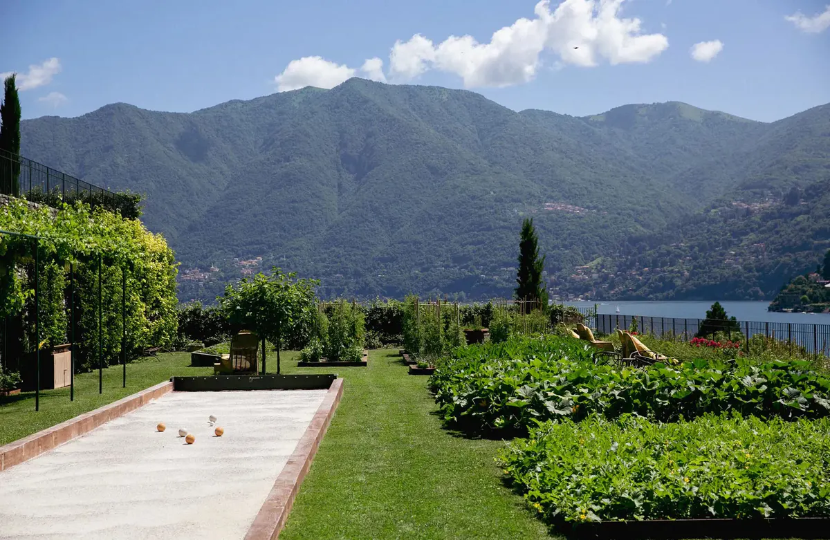 Manicured lawn with bocce court, cypress trees, and distant lake
