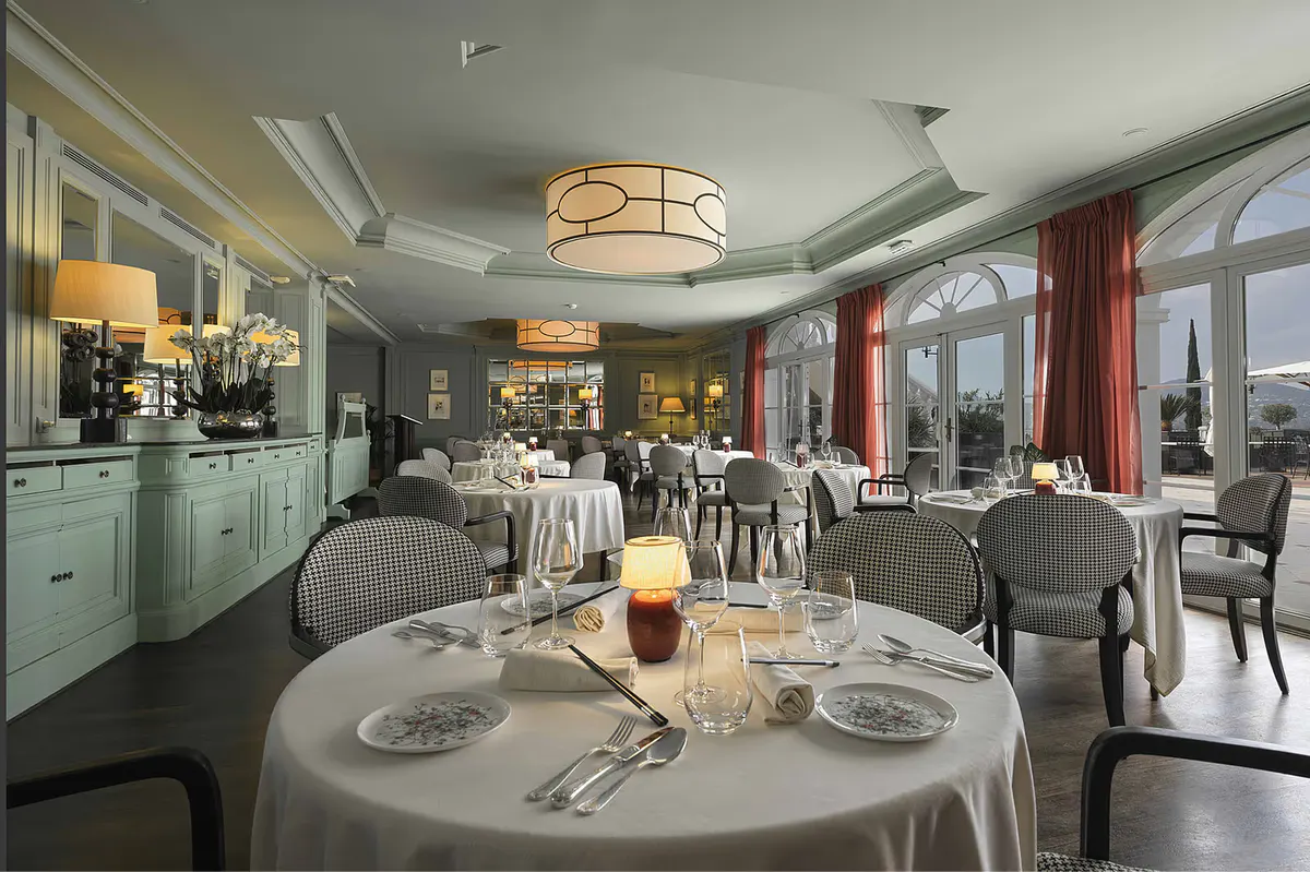Fine dining room with round table set with white linens and sea-view doors