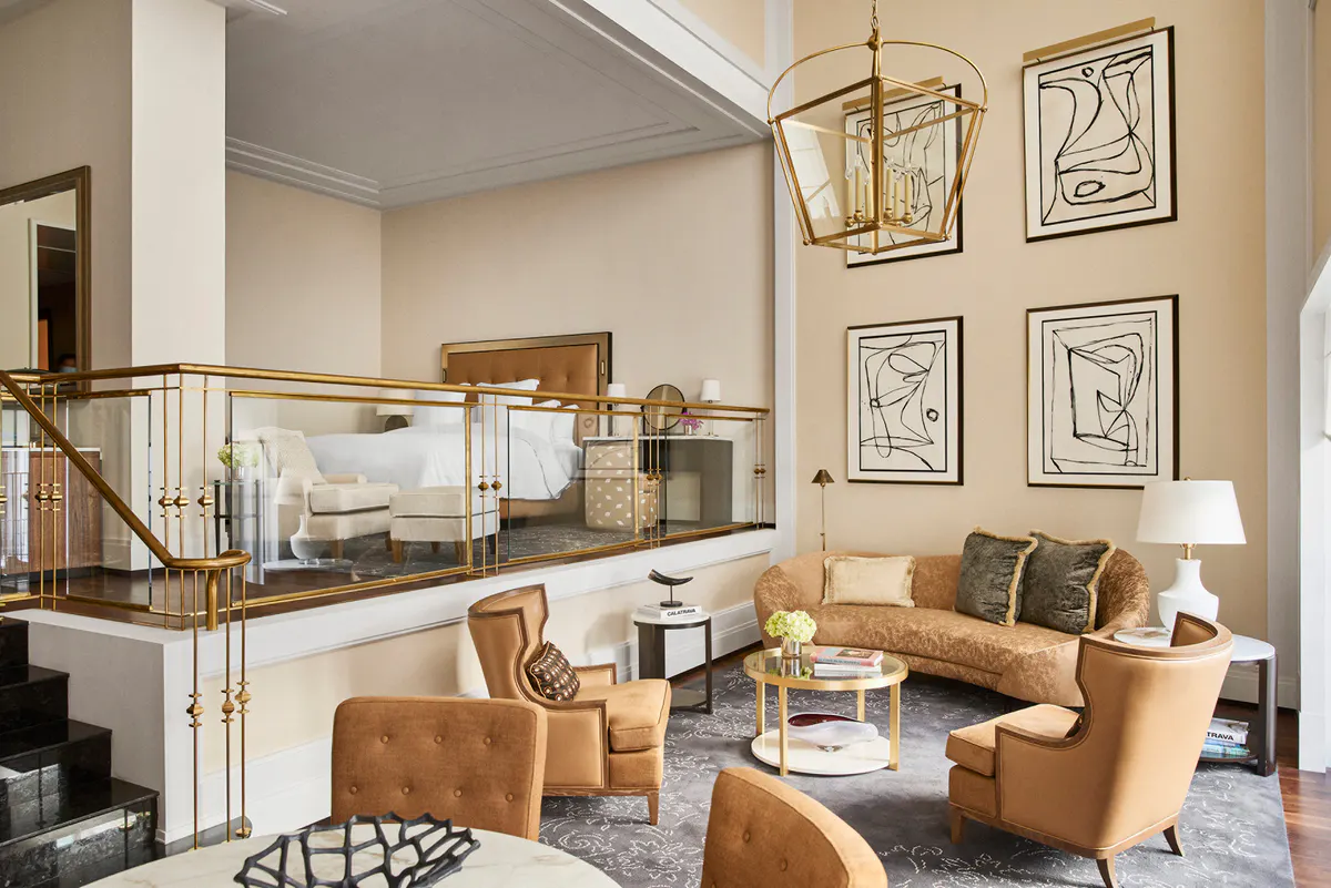 Suite with mezzanine level, tan leather seating, glass railings, and artwork on walls