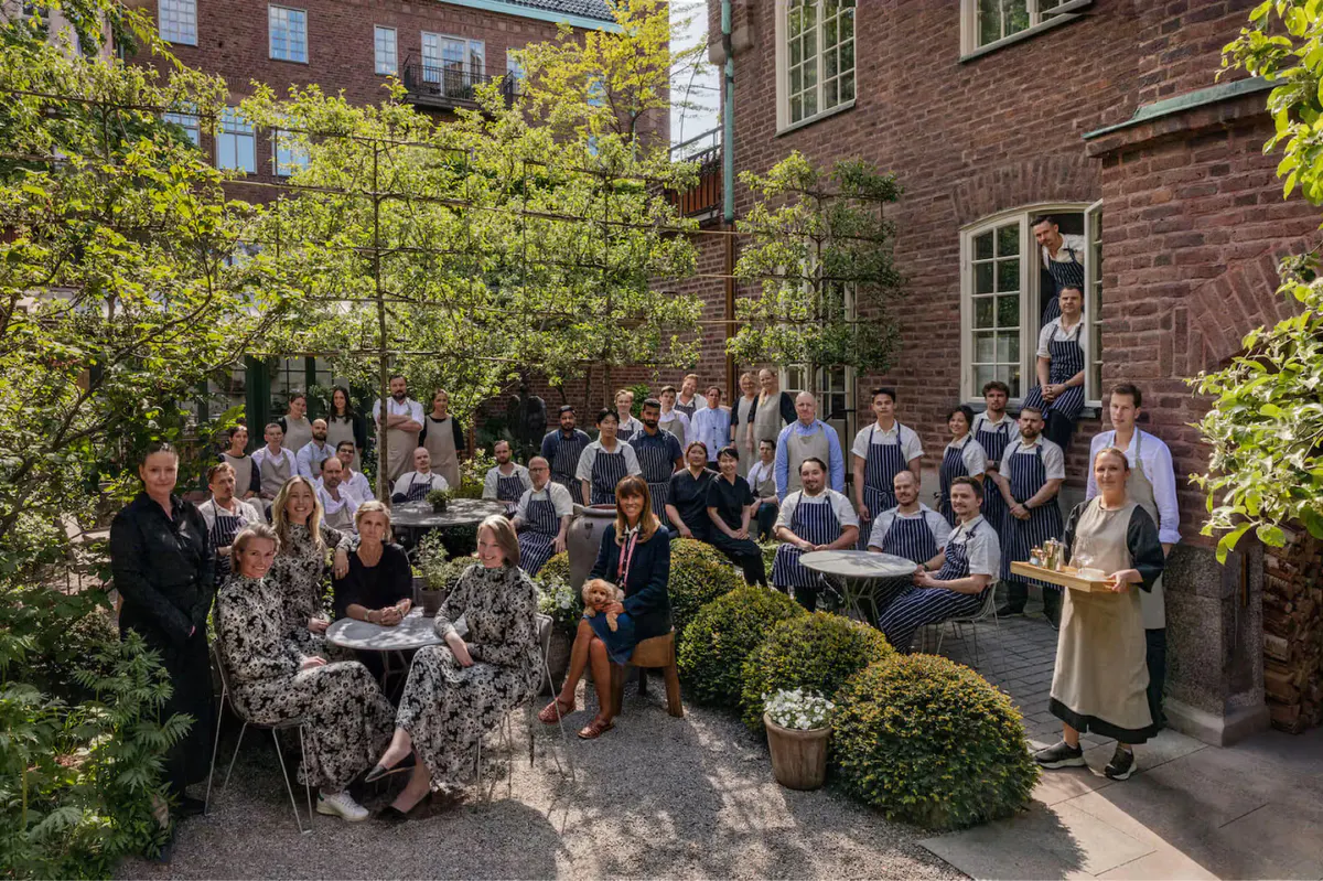 Guests gathered in a brick courtyard garden with trees and period architecture