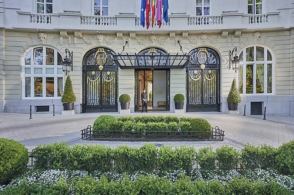 Elegant neoclassical entrance facade with manicured gardens and arched doors