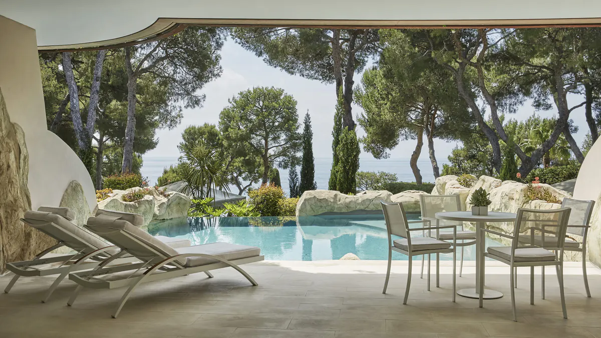 Shaded poolside lounge with Mediterranean plantings and sea horizon