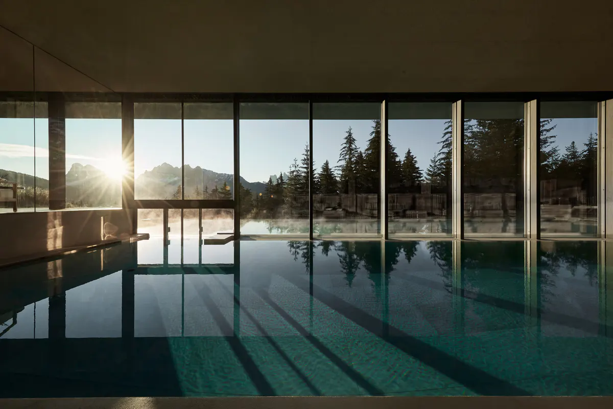 A dining or reception area with modern furnishings and mountain views through expansive glass