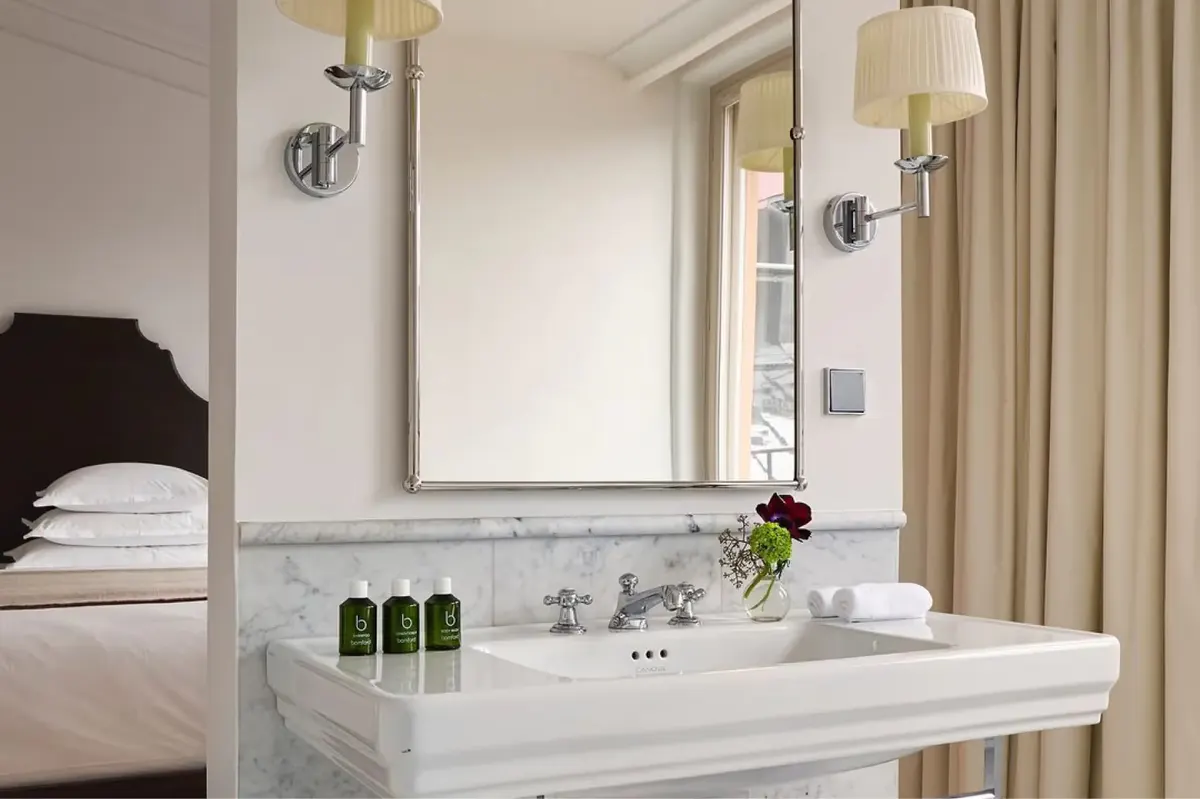 Marble bathroom sink with mirror, brass fixtures, and spa-quality amenities