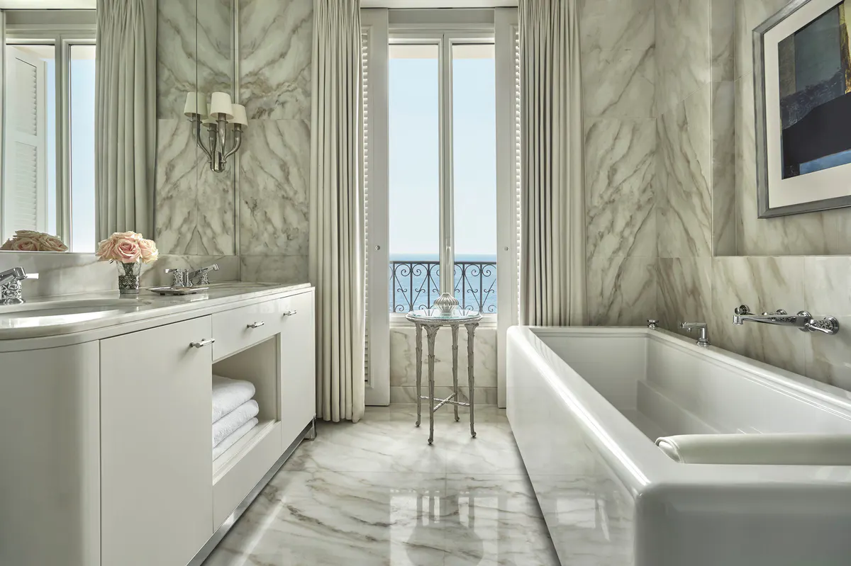 Marble bathroom with soaking tub positioned toward a sea-view window