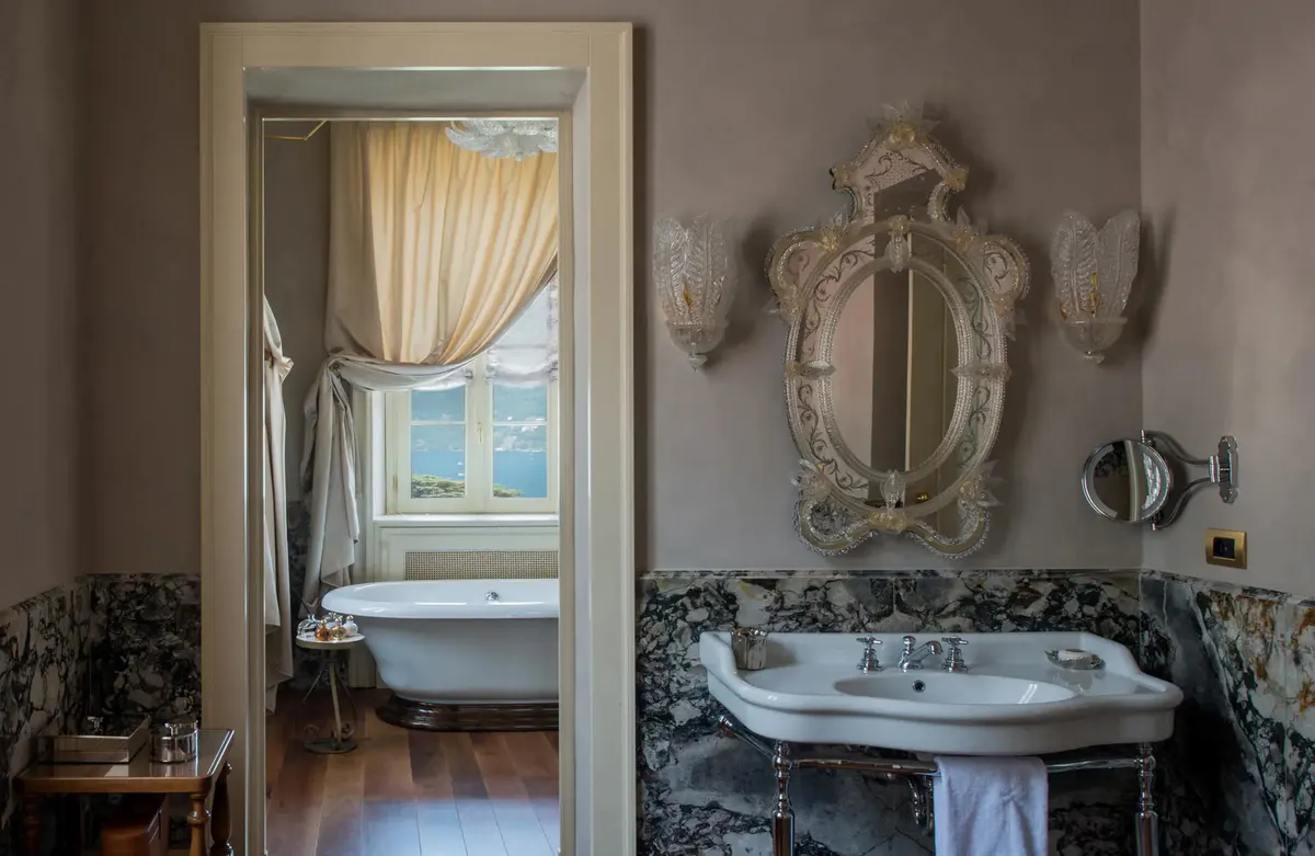 A bathroom viewed through an arched doorway with ornate sink and mirror