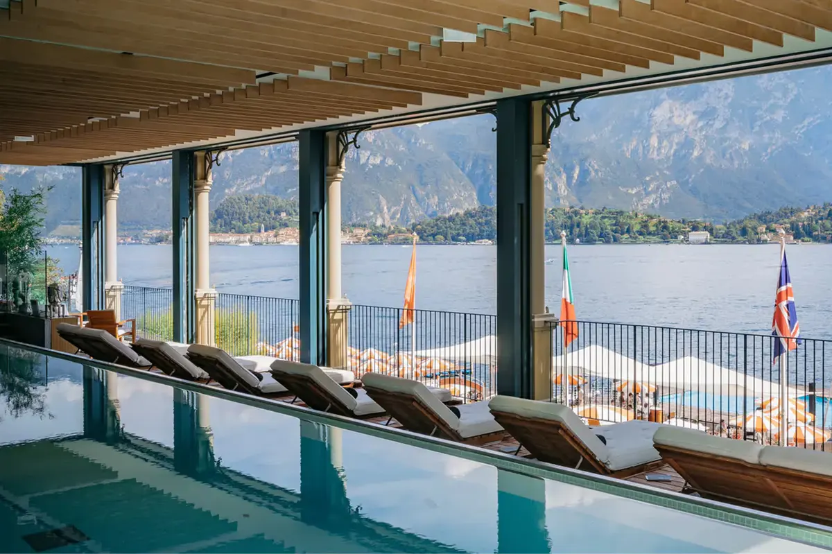 Indoor pool area with large windows framing lake and mountain views