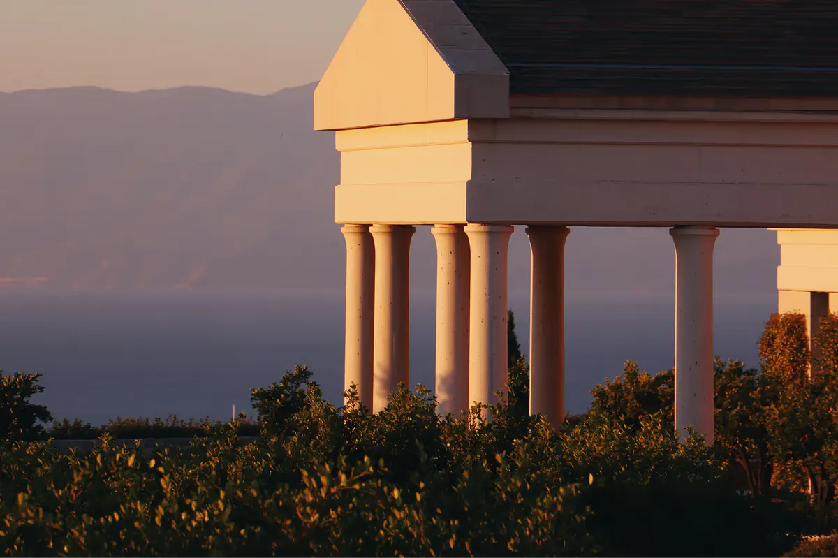 Illuminated columnwork with mountains and water at twilight