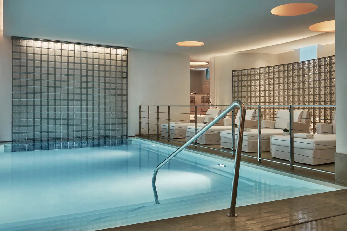 Indoor pool with blue tile and tall glass windows