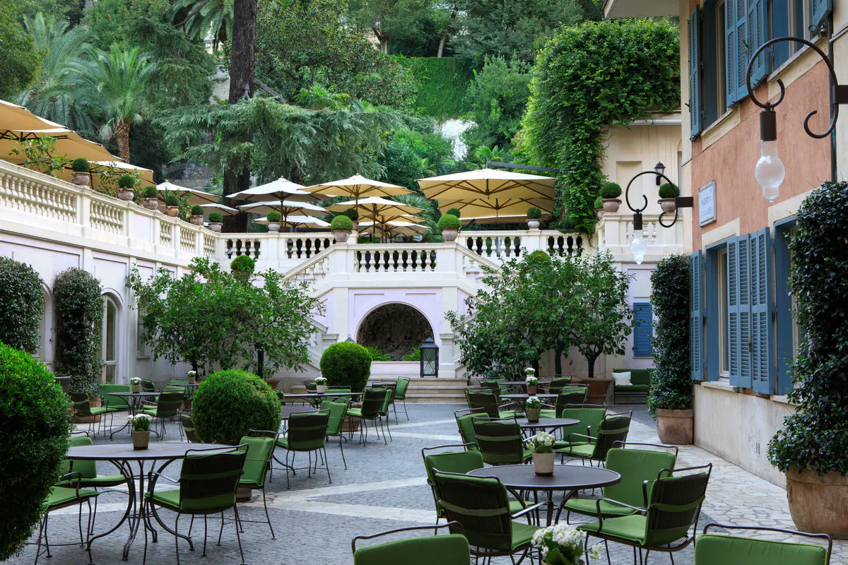 Tiered garden courtyard with columns, greenery, and scattered seating areas