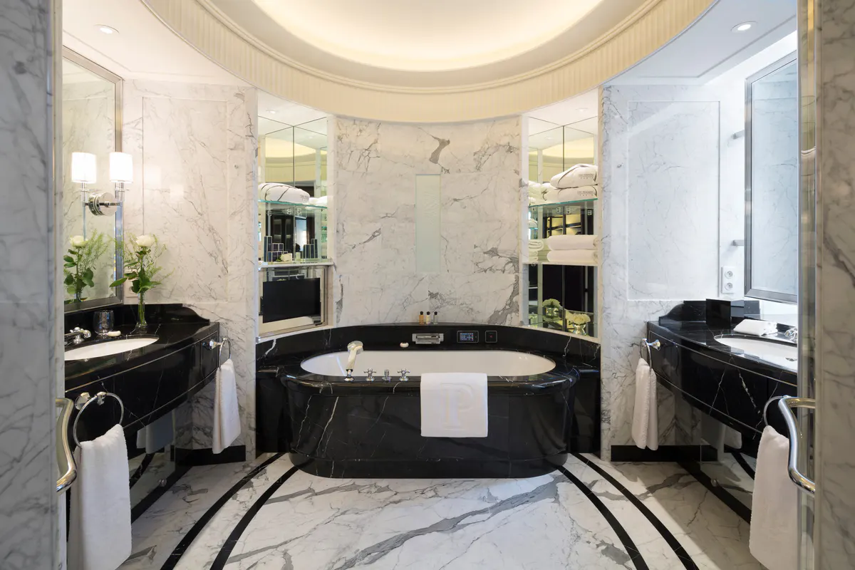 Bathroom with a black marble oval soaking tub centered under a curved ceiling with concealed lighting