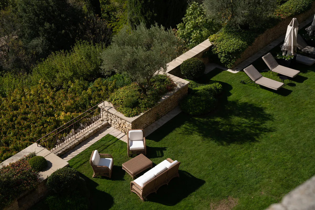 Terraced gardens sloping downward with stone walls and cypress punctuating the landscape