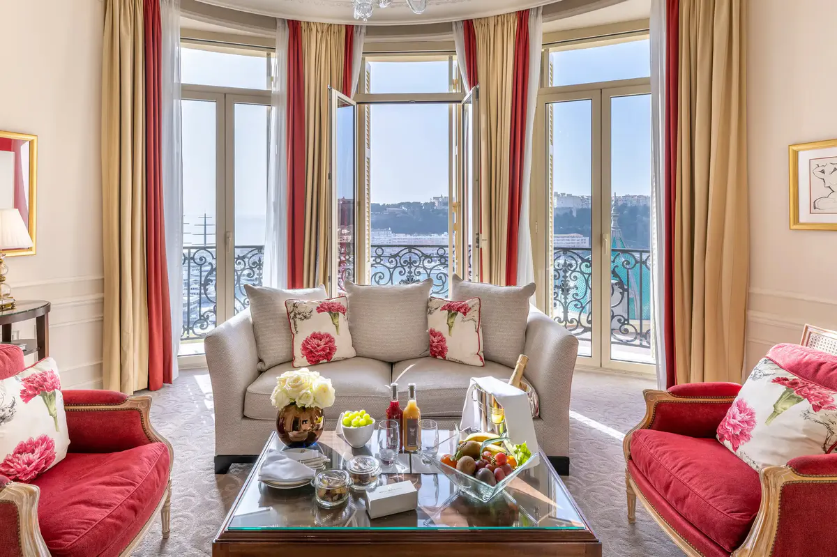 Living room with pink upholstered seating, arched windows and panoramic Mediterranean view