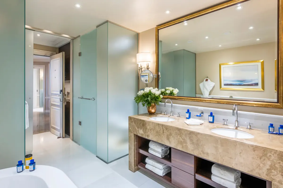 Marble bathroom with soaking tub, brass wall sconce and warm lighting