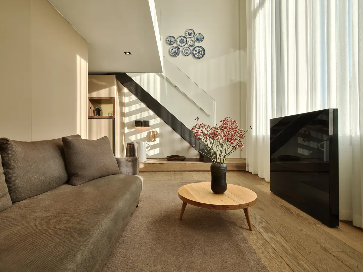 Light-filled loft space with staircase, wood flooring, and living area with greenery