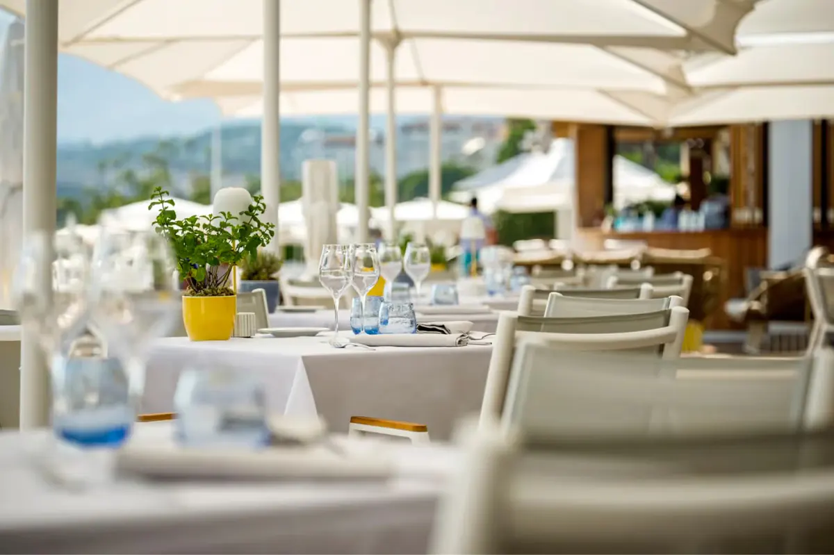 Dining table setup with white linens and a yellow flower arrangement overlooking mountain and sea views