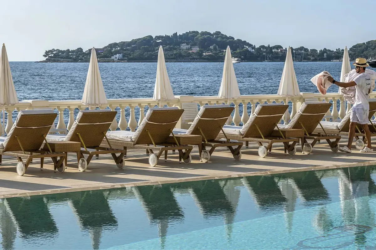 Terraced pool with deck chairs and sailboats on the Mediterranean