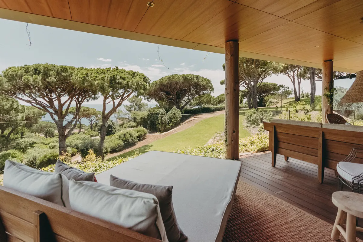 Shaded terrace with wooden furniture and Mediterranean landscape in distance