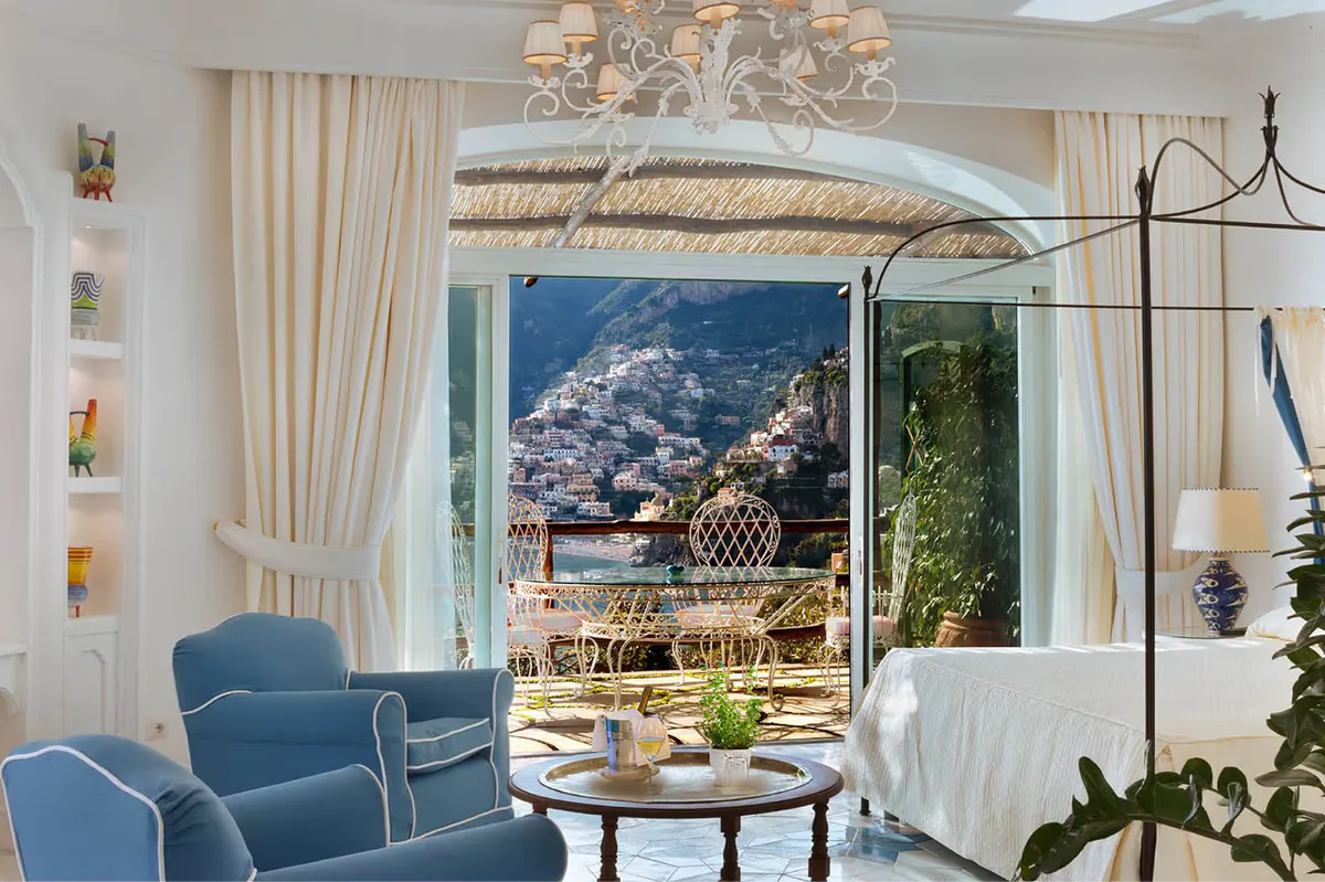 Bedroom with draped canopy, full windows, curved architectural details, and expansive coastal outlook