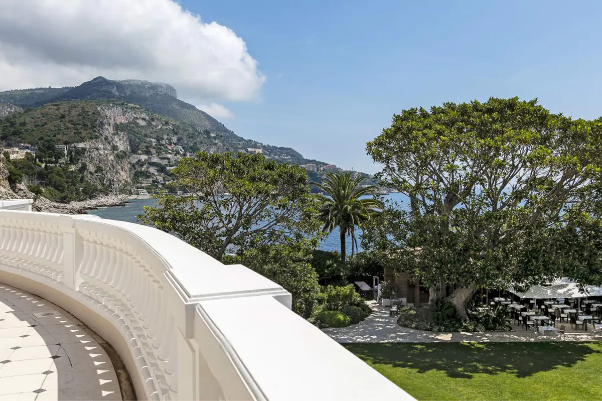 Curved white railing against a hillside and Mediterranean shoreline