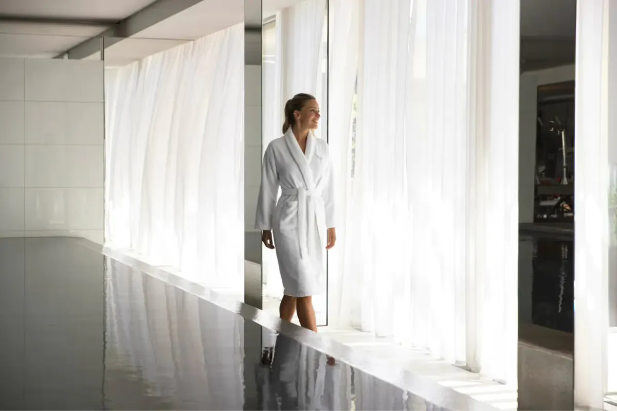 Spa therapist in white uniform in bright spa treatment corridor