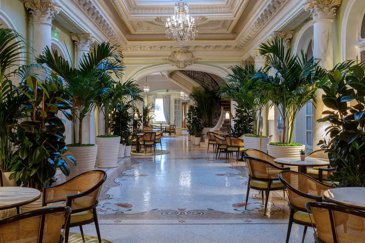 Grand hallway with coffered ceiling, crystal chandelier, palm trees and marble flooring