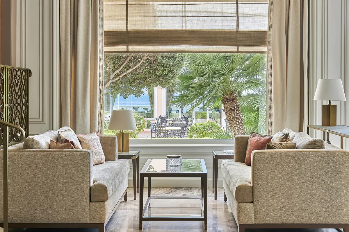 Lounge area with floor-to-ceiling windows overlooking green gardens