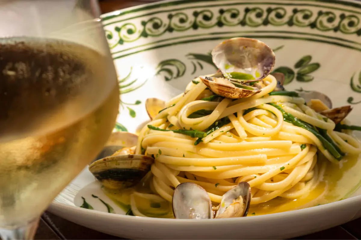 Handmade fresh pasta on a decorative plate with herbs and coastal light