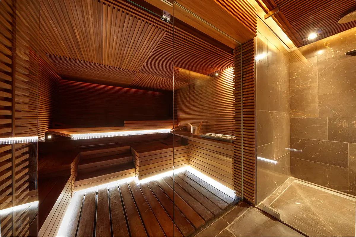 Sauna room with wooden slat interior, bench seating, and frosted glass steam room entrance