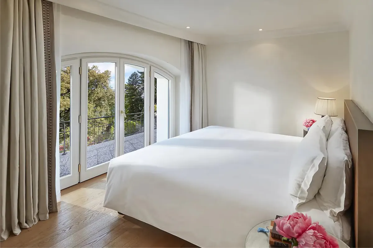 Bedroom with white duvet, wood details, and wide windows framing mountain vista