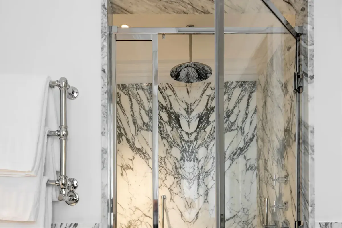 Glass shower enclosure with marble walls and rain showerhead