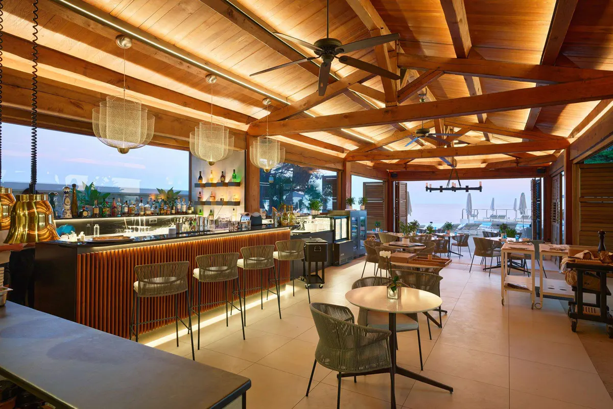 A bar area with wooden slat surfaces and views to the sea