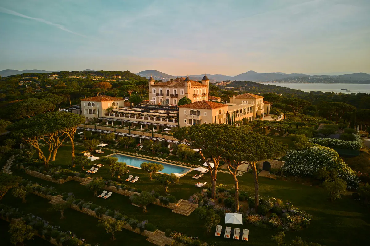 Hilltop château with manicured grounds and blue swimming pools overlooking Mediterranean coast