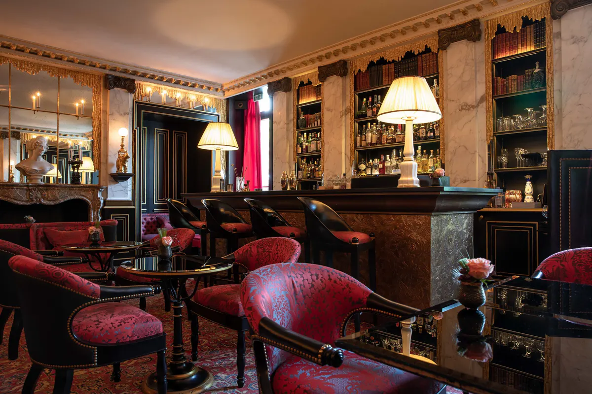 An intimate lounge with burgundy velvet seating and warm oak cabinetry