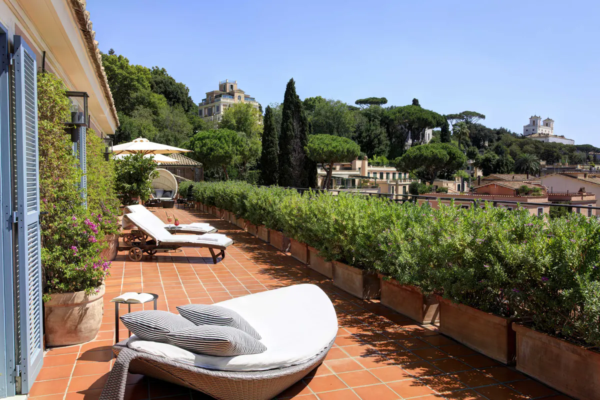 Terracotta rooftop seating with loungers and city views at sunset