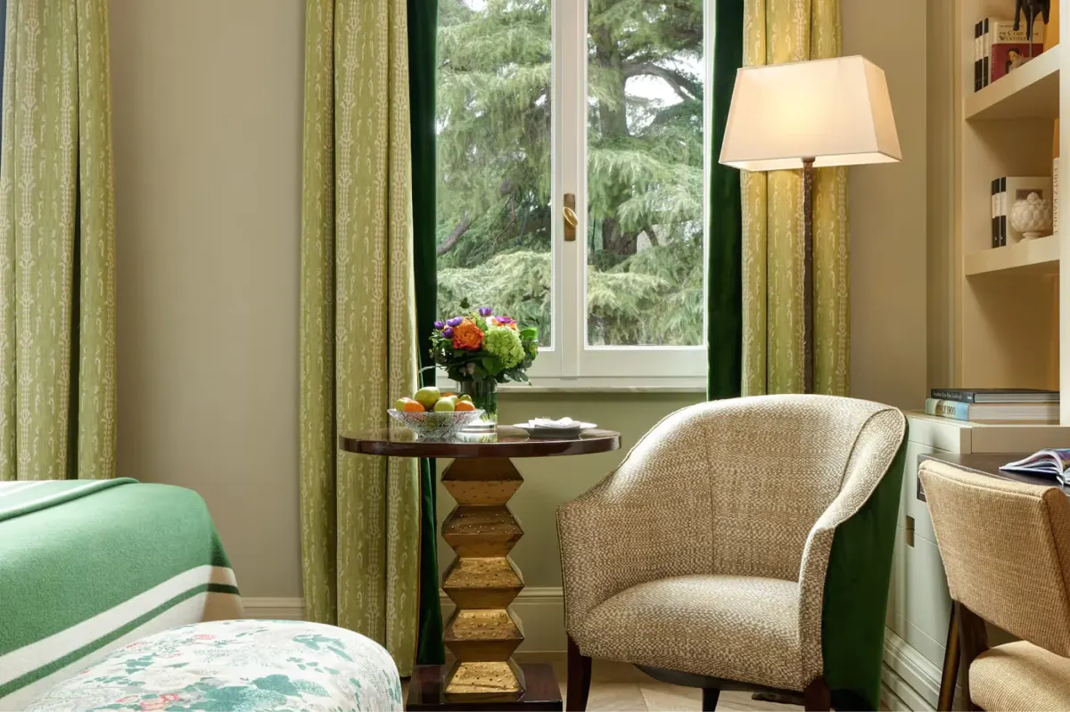 Bedroom corner with green curtains, armchair, and bedside lamp near window