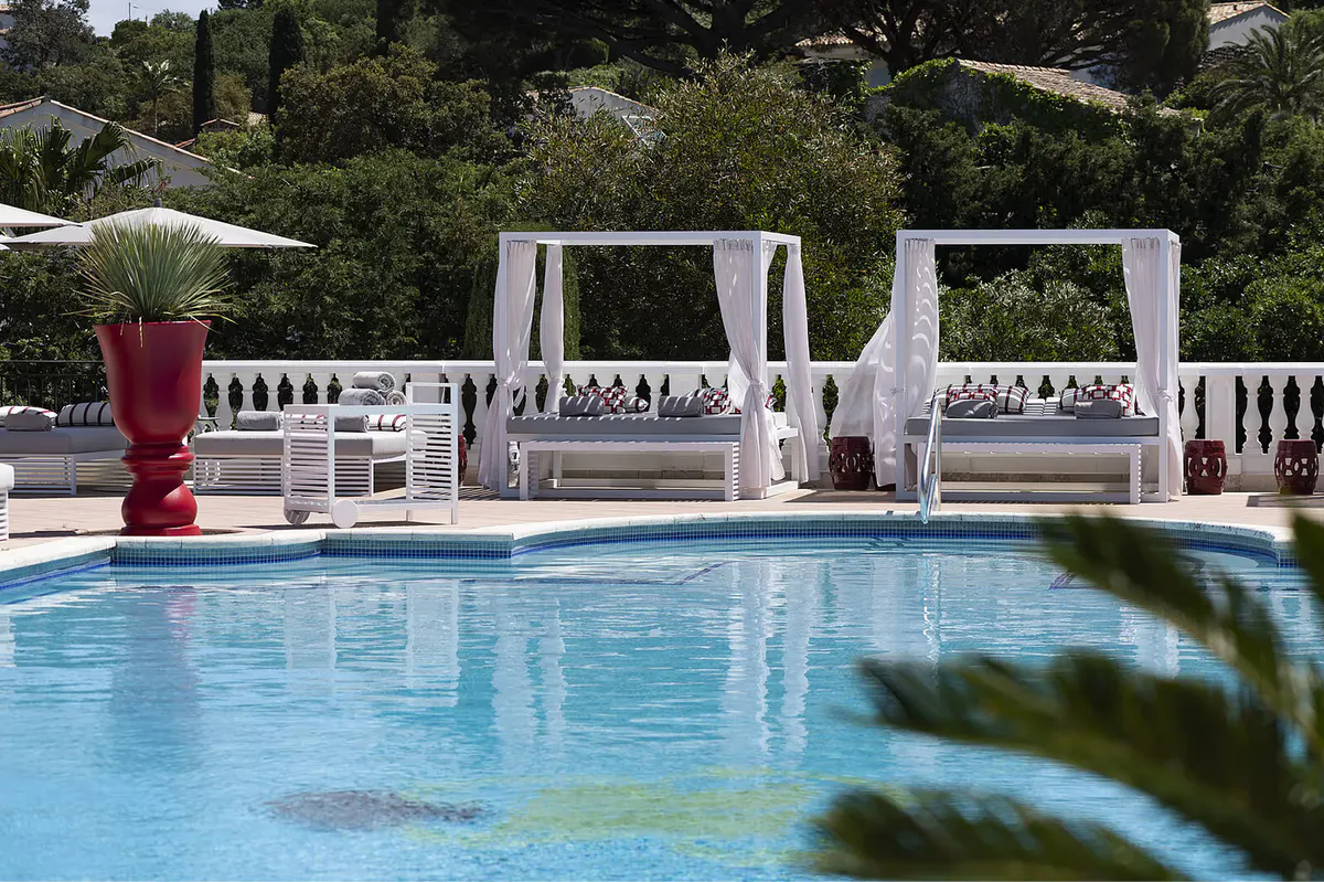 Pool deck with white cabanas and striped loungers overlooking the bay