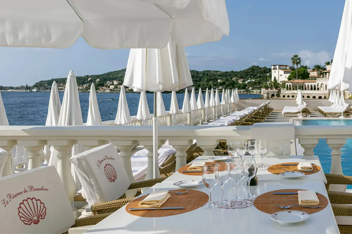Beachside dining setup with table settings and Mediterranean vista