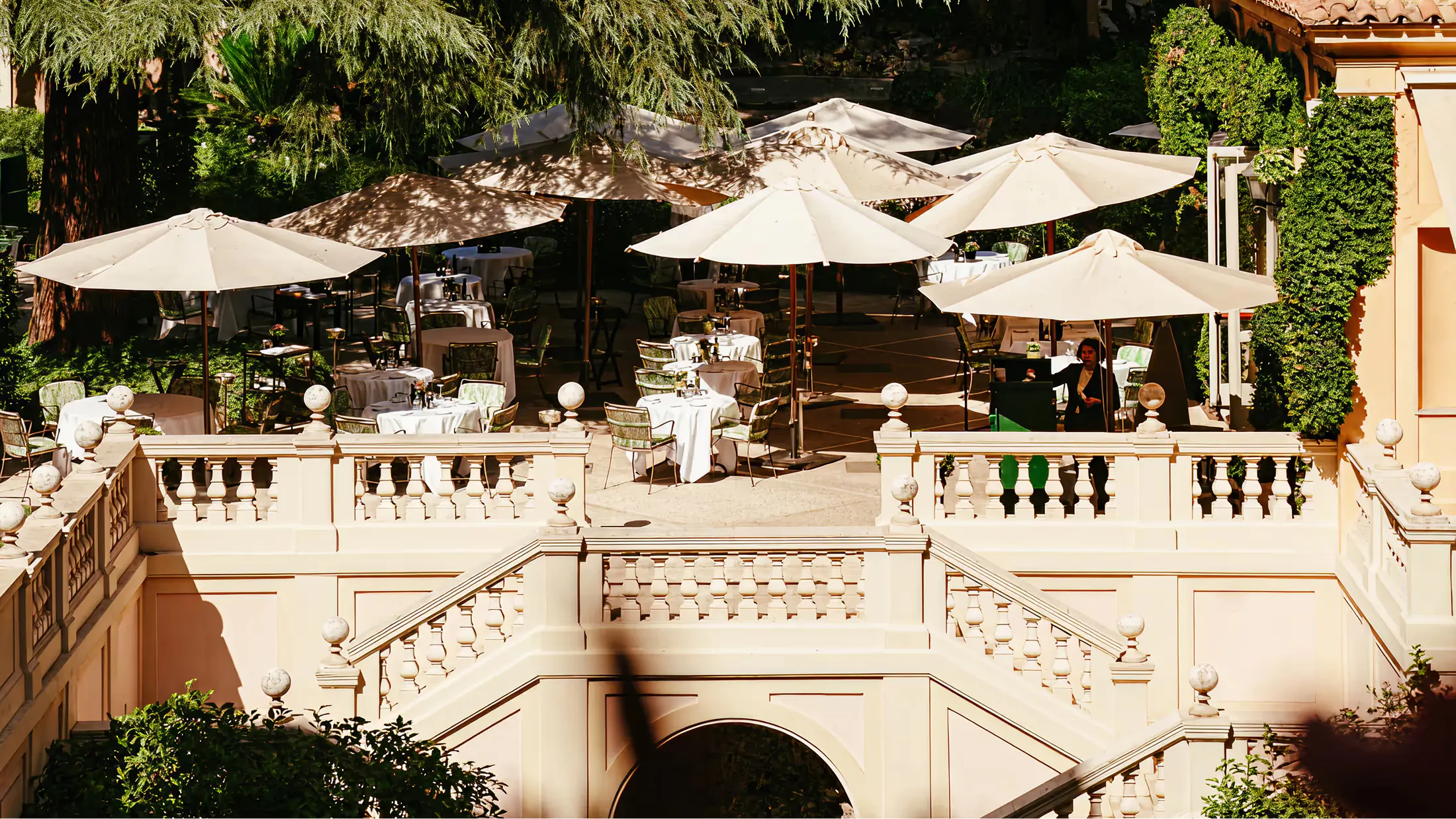 Tiered garden terrace with cream-colored umbrellas overlooking Rome