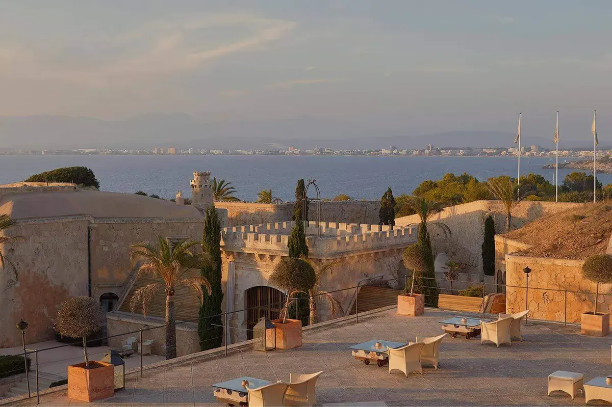 A hilltop fortress silhouetted at sunset, with panoramic bay views and cypress sentries
