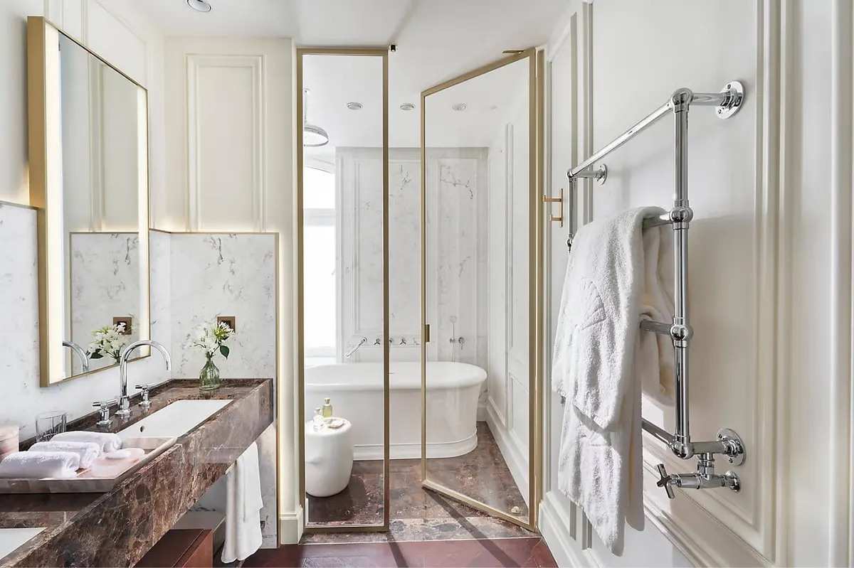 Marble bathroom with glass-enclosed shower and heated towel racks