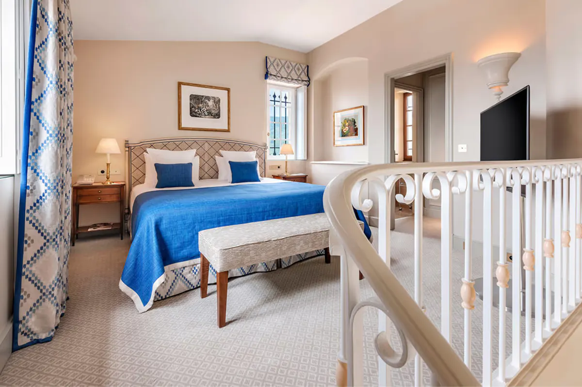 Suite bedroom with blue bedding, fireplace, and child’s crib
