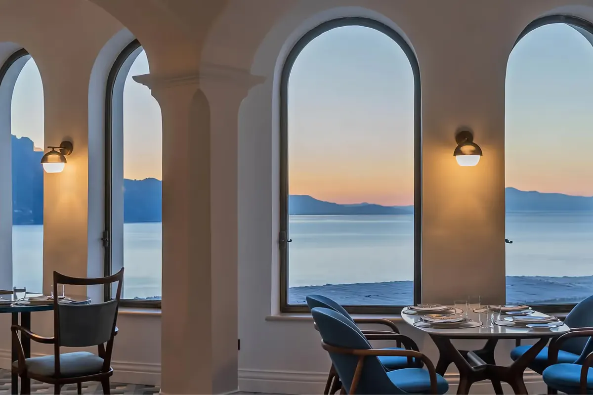 Indoor dining room with arched openings overlooking sunset seascape