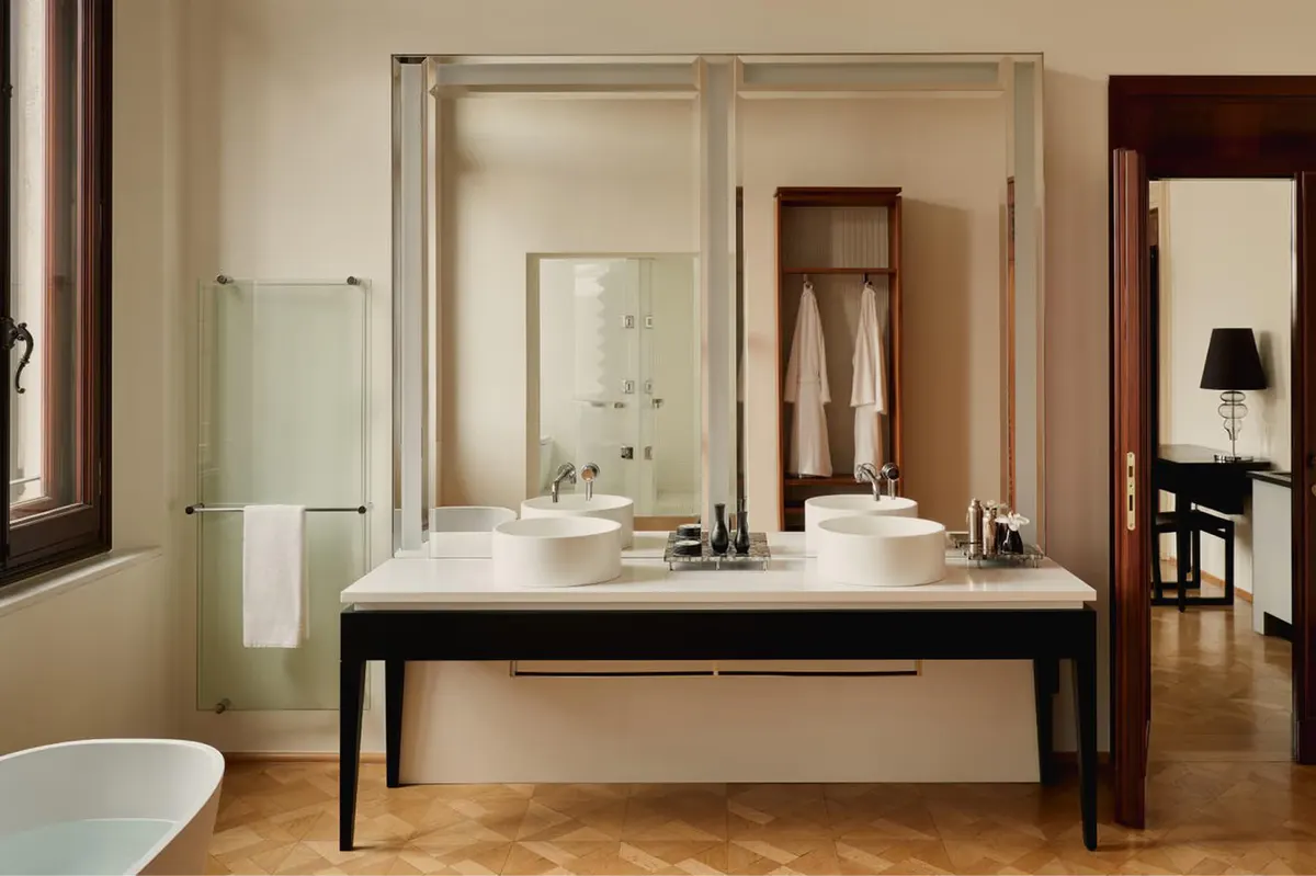 A spa bathroom with double marble vanity, large mirror, glass enclosure, and wooden flooring