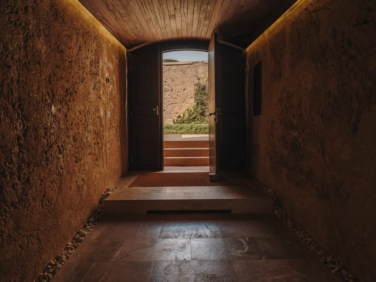 A dark stone corridor frames coastal light and vegetation beyond, in fortress architecture